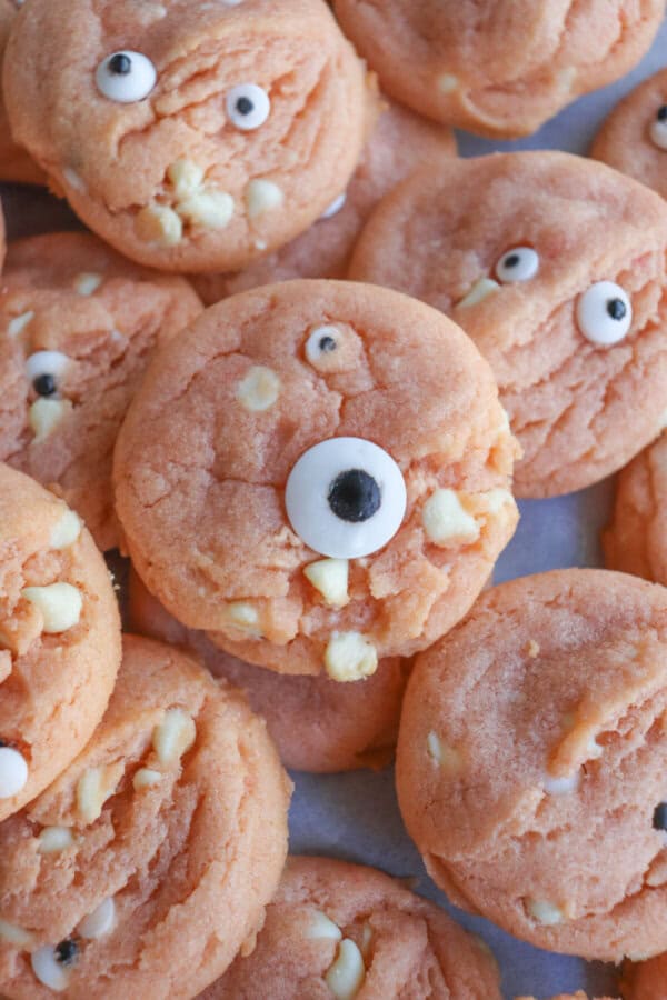 Orange pudding cookies with candy eyes stacked on top of each other.