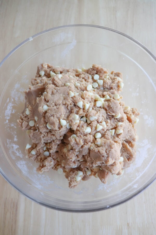 Pumpkin spice pudding cookie dough with white chocolate chips in a clear mixing bowl.