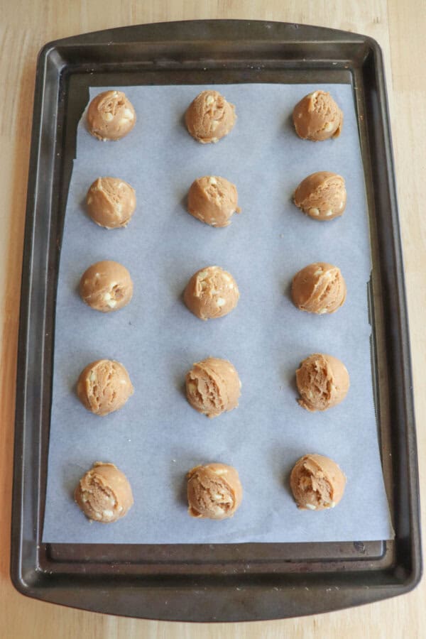 Pumpkin spice cookie dough balls on a parchment paper lined baking sheet.