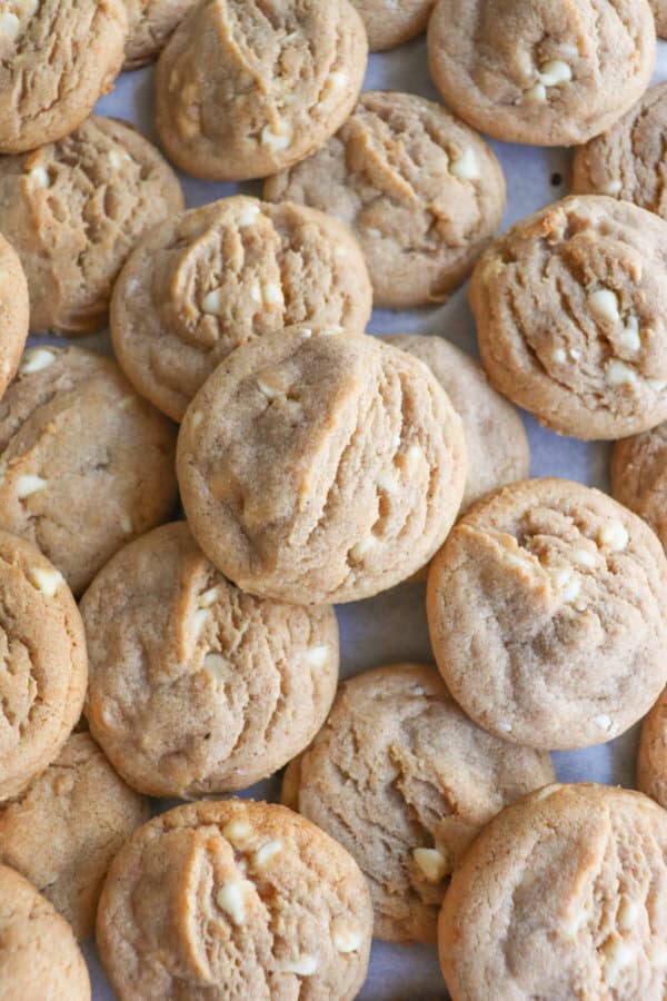 Caramel colored pumpkin spice cookies with white chocolate chips layered on top of each other.