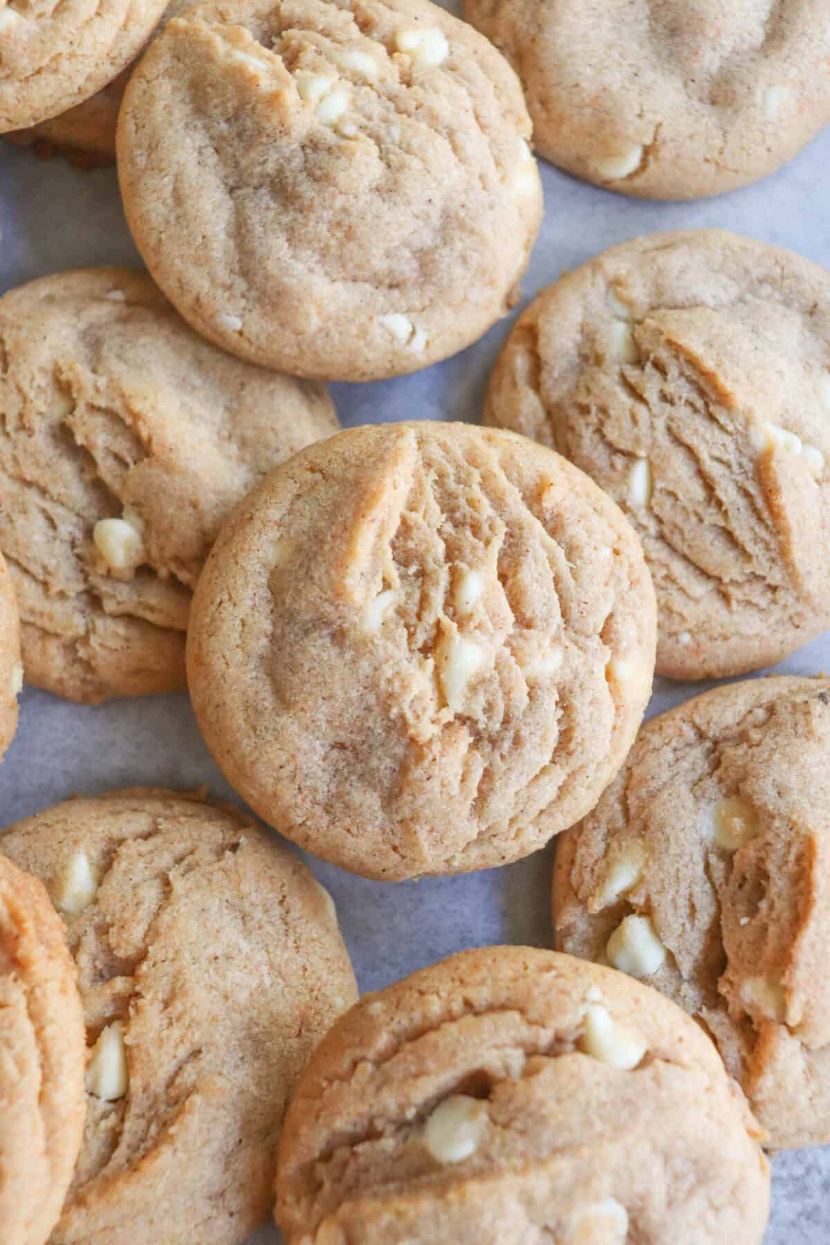 Caramel colored pumpkin spice cookies with white chocolate chips layered on top of each other.