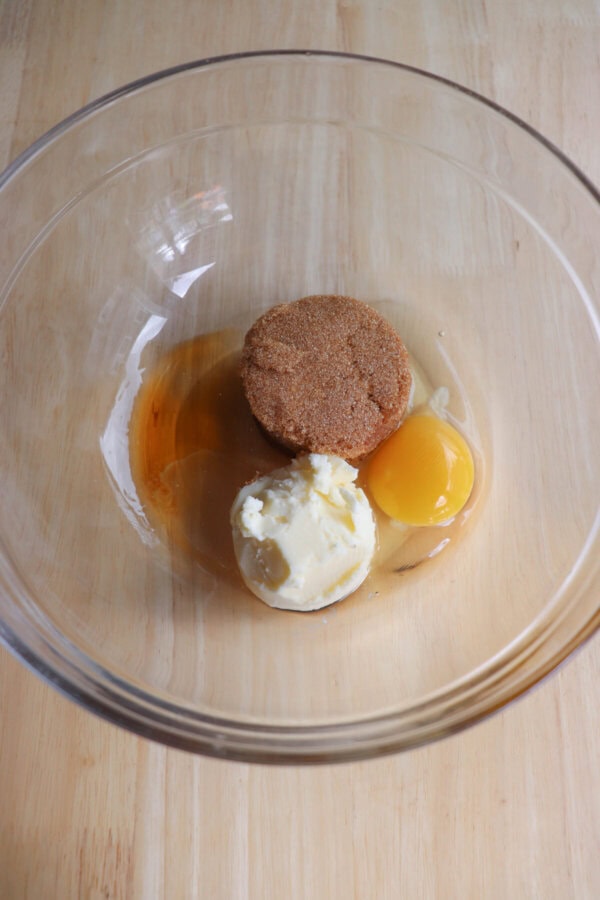Butter, sugar and egg in a clear glass mixing bowl.