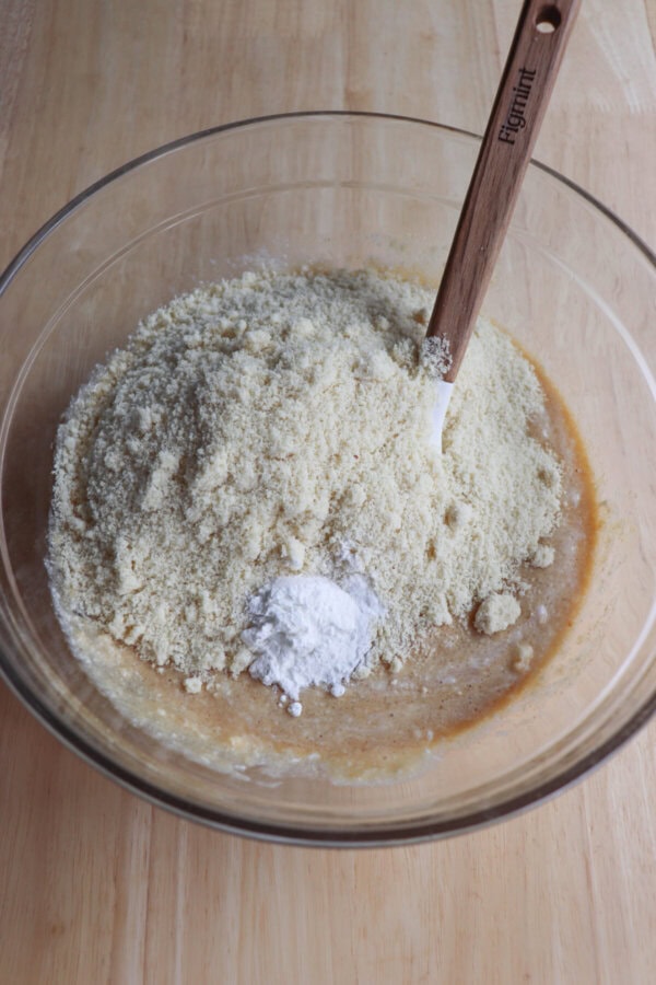 Wet and dry ingredients for cottage cheese cookies in a clear glass mixing bowl.