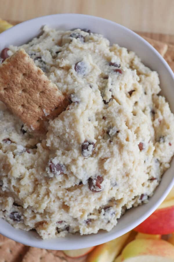 Cottage cheese cookie dough dip in a white bowl surrounded by graham crackers and apple slices.