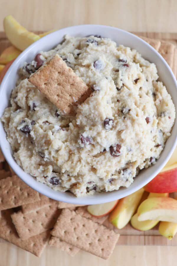 Cottage cheese cookie dough dip in a white bowl surrounded by graham crackers and apple slices.