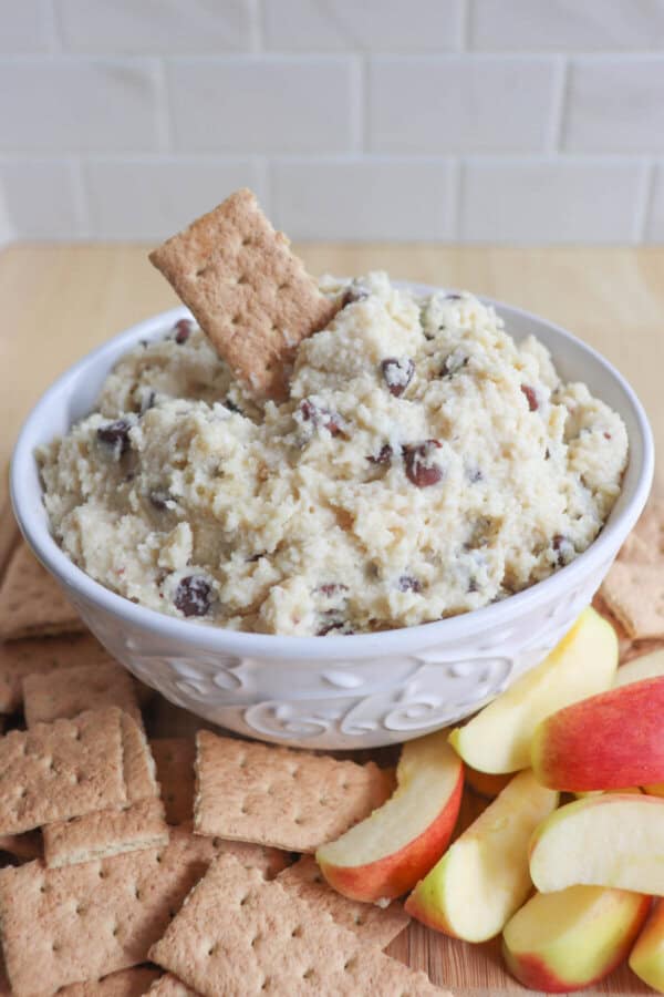 Cottage cheese cookie dough dip in a white bowl surrounded by graham crackers and apple slices.
