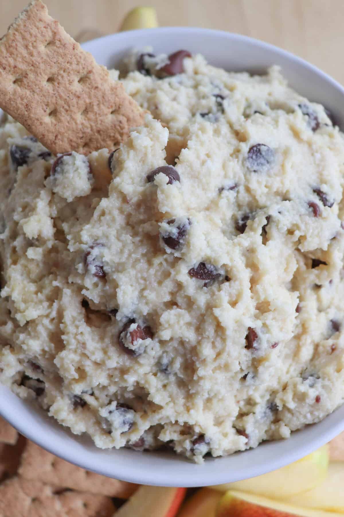 Cottage cheese cookie dough dip in a white bowl with a graham cracker being dipped.