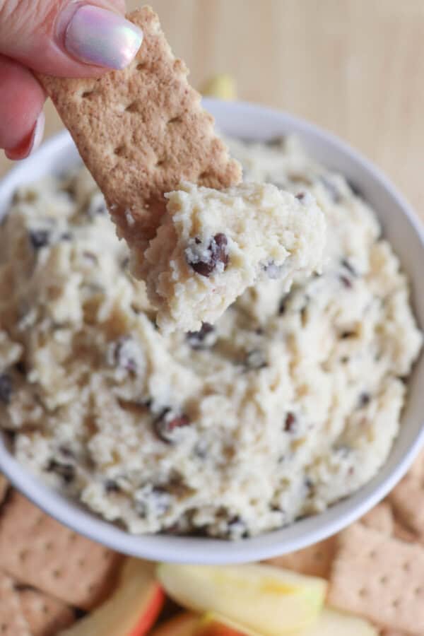 Cottage cheese cookie dough dip in a white bowl surrounded by graham crackers and apple slices.