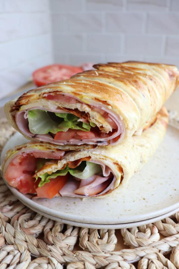 Cottage cheese flatbread wrap filled with ham, tomato and lettuce on a white plate.