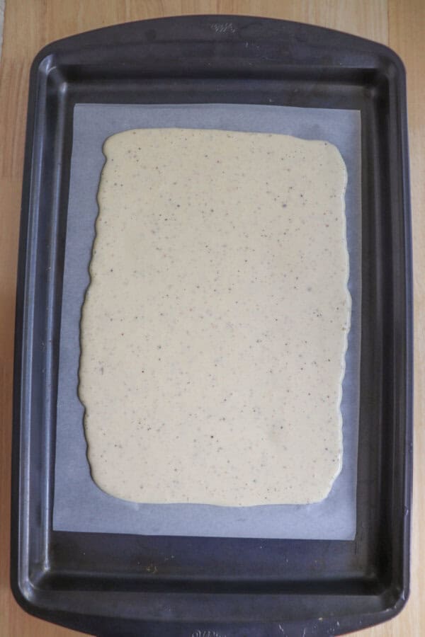 Cottage cheese flatbread mixture spread out onto a parchment paper lined baking sheet.