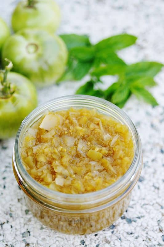 Green tomato relish in a clear glass jar.