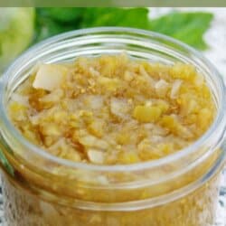 Green tomato relish in a clear glass jar.