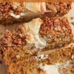 Pumpkin bread, filled with cream cheese with a strussel topping, cut into slices on a wooden board.