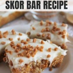 Gooey bars with vanilla frosting sprinkled with skor bits on a white plate.