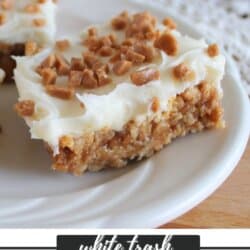 Gooey bars with vanilla frosting sprinkled with skor bits on a white plate.