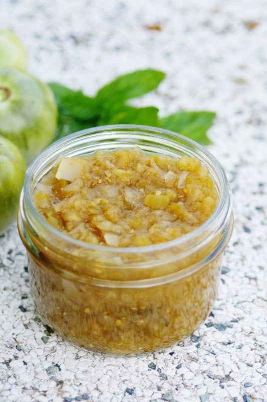 Green tomato relish in a clear glass jar.