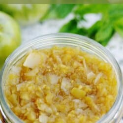 Green tomato relish in a clear glass jar.