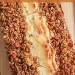 Pumpkin bread, filled with cream cheese with a strussel topping on a wooden cutting board.