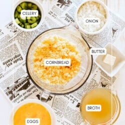 Ingredients for cornbread stuffing in clear glass bowls on a newspaper lined table.
