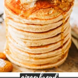 Fluffy gingerbread pancakes stacked on top of each other with a pat of butter on top and syrup dripping over the edges.