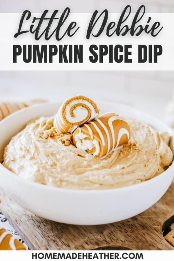 Creamy pumpkin spice dip in a white bowl topped with Little Debbie pumpkin rolls on a newspaper lined table.