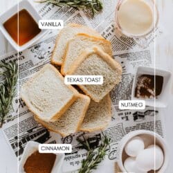 Top view of ingredients for French toast on a wooden surface, including slices of Texas toast, a glass of eggnog, bowls of vanilla extract, nutmeg, cinnamon, and whole eggs. Sprigs of rosemary and a newspaper complete the setup.