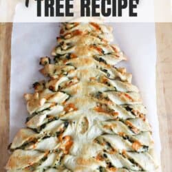 Spinach dip in dough in the shape of a Christmas tree on a parchment paper lined wooden cutting board.