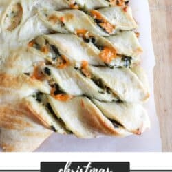 Spinach dip in dough in the shape of a Christmas tree on a parchment paper lined wooden cutting board.