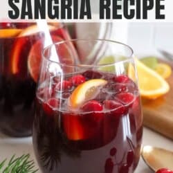 Red wine sangria in a clear glass pitcher with cranberries, lime slices and orange slices for garnish.