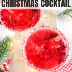 Red drink in a cocktail glass with candy cane garnish and ice.
