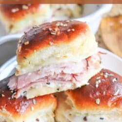 Three Ham & Swiss Sliders stacked on a a white plate.