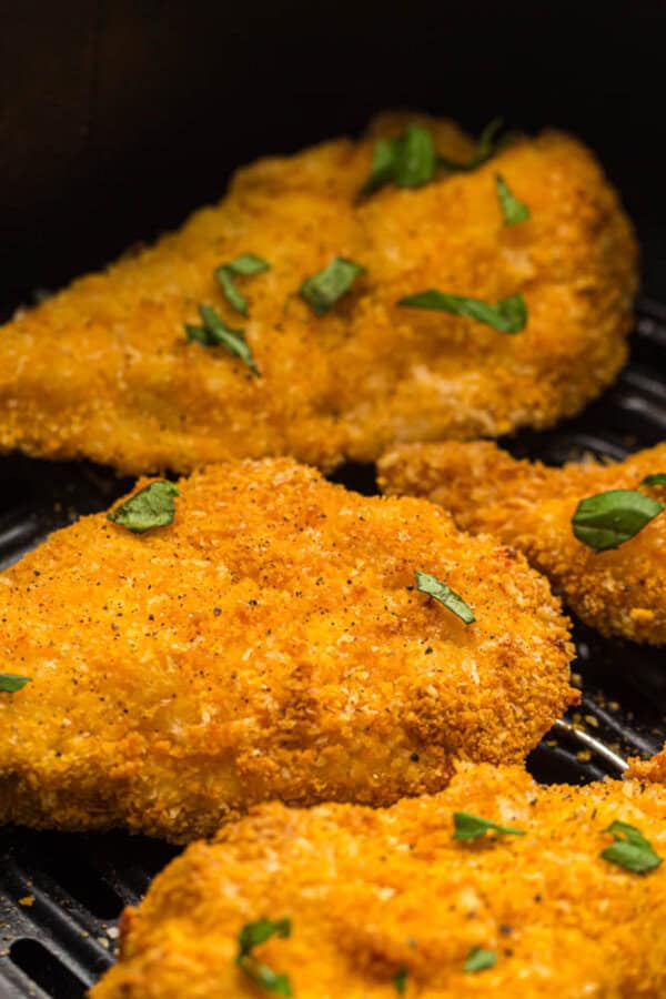 Breaded chicken strips in the basket of an air fryer.