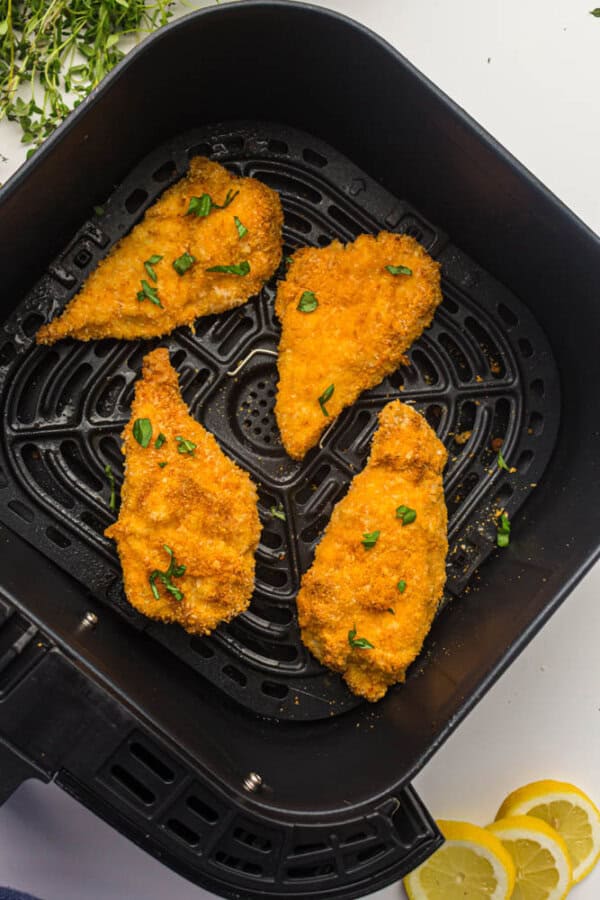 Breaded chicken strips in the basket of an air fryer.