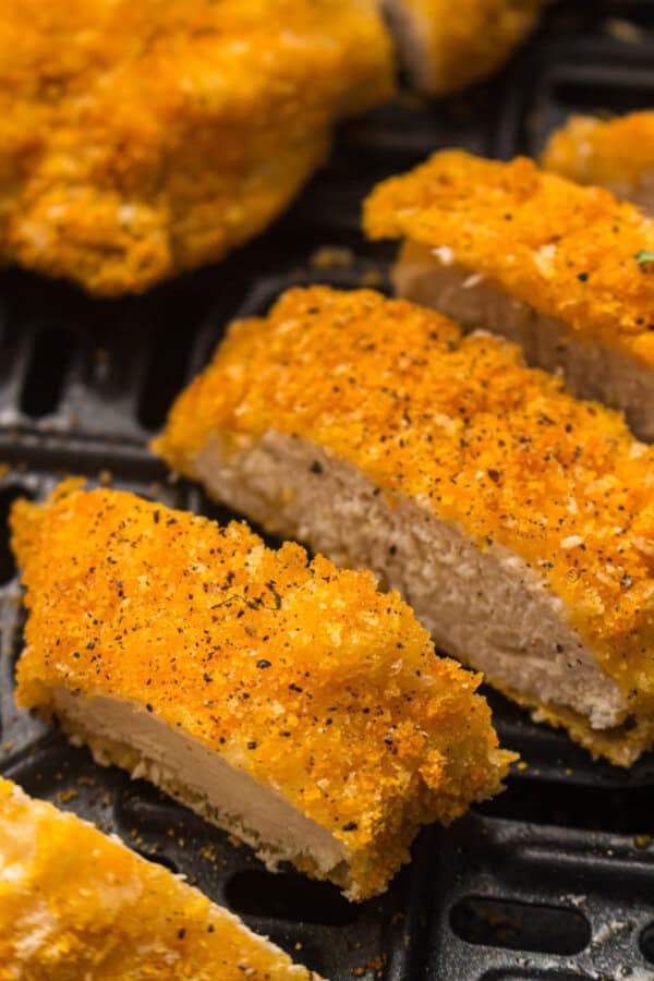 Breaded chicken strips in the basket of an air fryer.