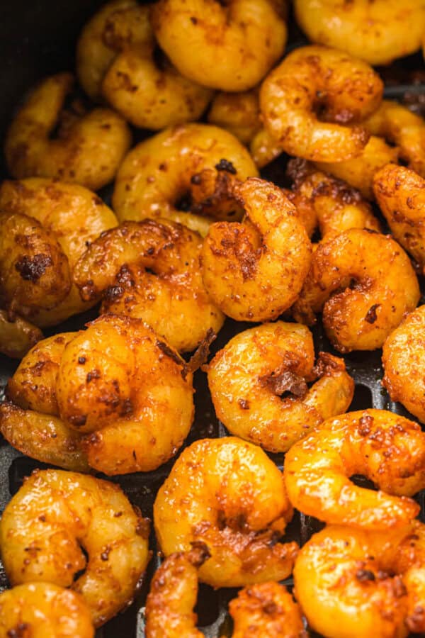 Close-up of golden-brown, seasoned shrimp cooked to perfection. The shrimp have a slightly crispy, caramelized coating and are piled together, showcasing their texture and appetizing appearance.