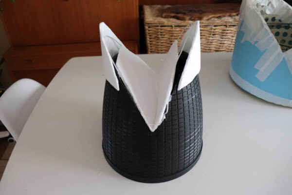 Black container with poster board attached to it on a white table.