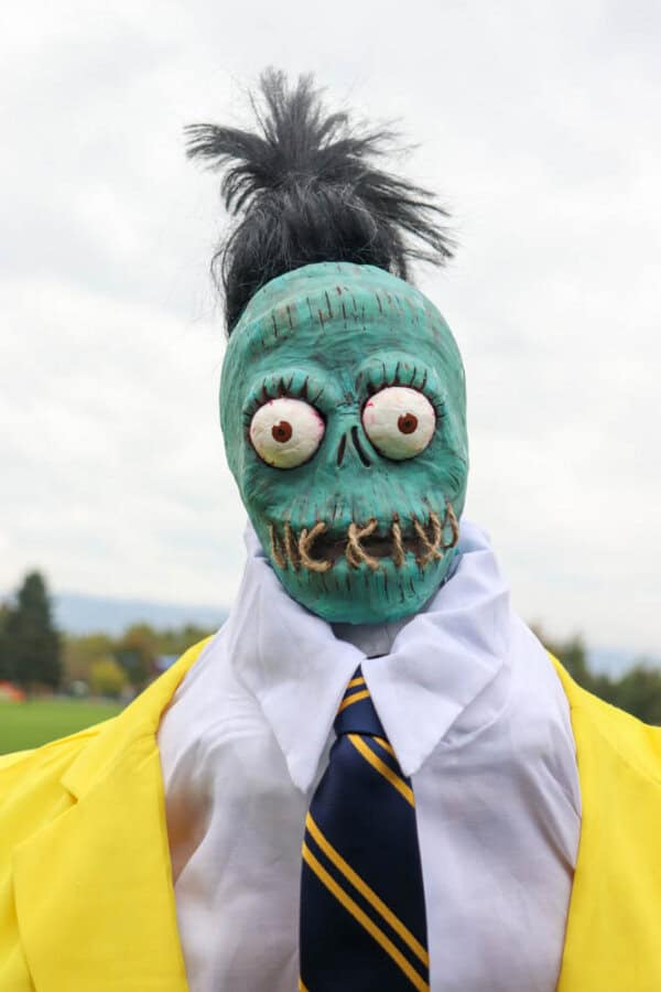 plague doctor costume Zombie shrunken head that looks like Bob from Beetlejuice with a white dress shirt and yellow suit.