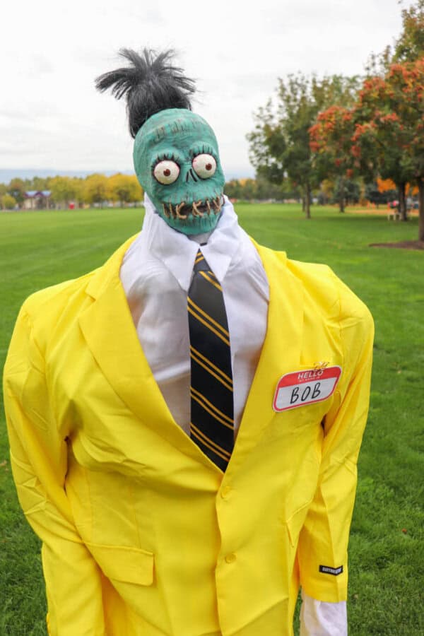 plague doctor costume Zombie shrunken head that looks like Bob from Beetlejuice with a white dress shirt and yellow suit.