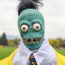 Zombie shrunken head that looks like Bob from Beetlejuice with a white dress shirt and yellow suit.