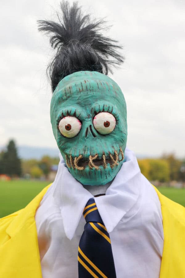 plague doctor costume Zombie shrunken head that looks like Bob from Beetlejuice with a white dress shirt and yellow suit.
