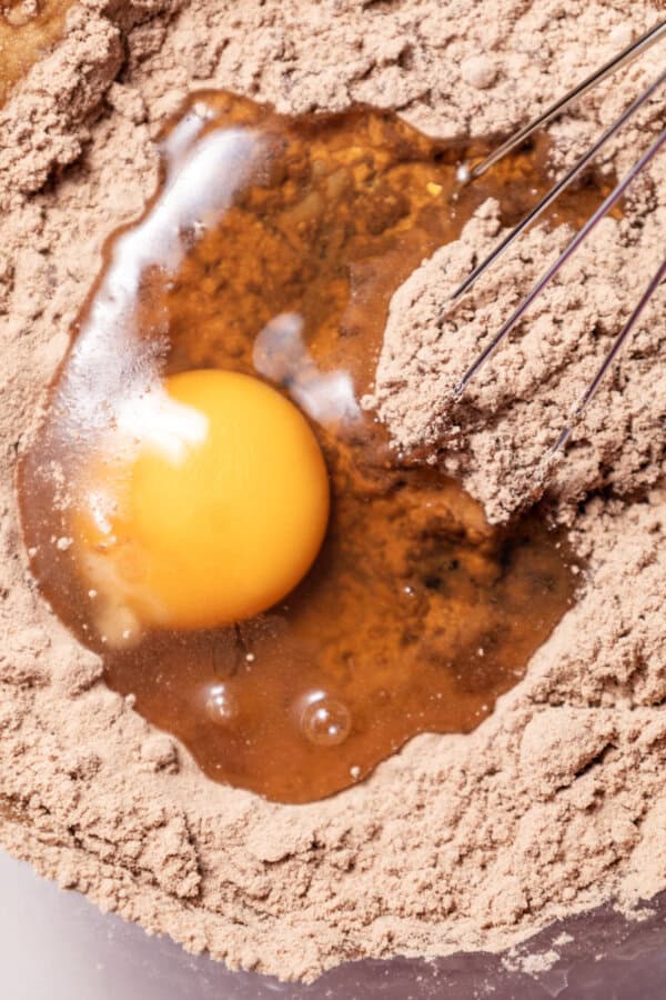 Dry ingredients and egg in a clear mixing bowl with a whisk.