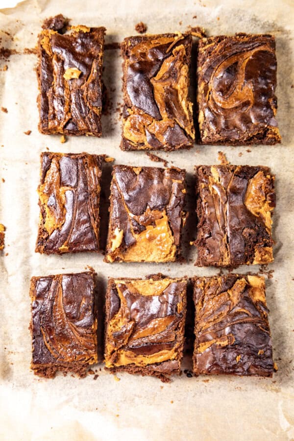 Baked Peanut Butter Brownies cut up into squares on parchment.