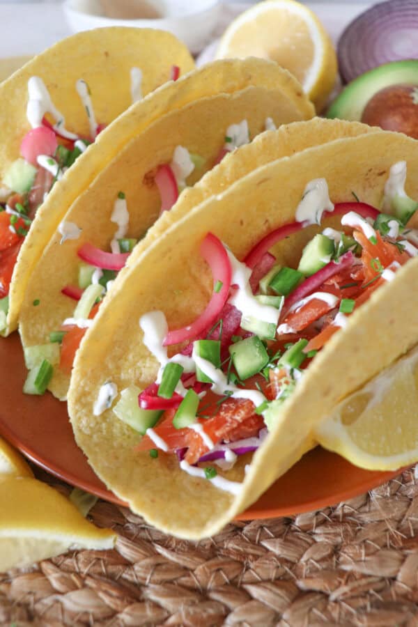 Corn tortillas filled with smoked salmon, diced cucumber, coleslaw and pickled red onions, garnished with dill and chives and topped with cilantro lime crema.