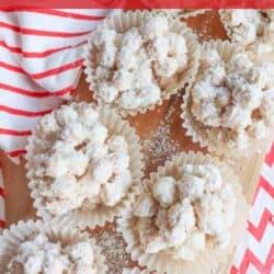 Top view of crockpot snowman balls crafted from a delightful recipe, nestled in parchment cups. They're dusted with powdered sugar and encircled by red and white striped decorations. Text at the top proudly announces: Crockpot Snowman Balls Recipe.