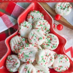 A festive display of white chocolate-dipped mints topped with red and green sprinkles arranged on a Christmas tree-shaped platter. Accompanied by a holiday-themed cloth and candy canes. Text reads: Christmas Mints Recipe and homemadeheather.com.