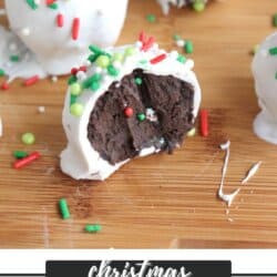Close-up of Christmas Oreo balls on a wooden surface. One is cut in half, revealing a chocolate center. The balls are coated in white icing and decorated with red, green, and white sprinkles. Text reads Christmas Oreo Balls with a website below.