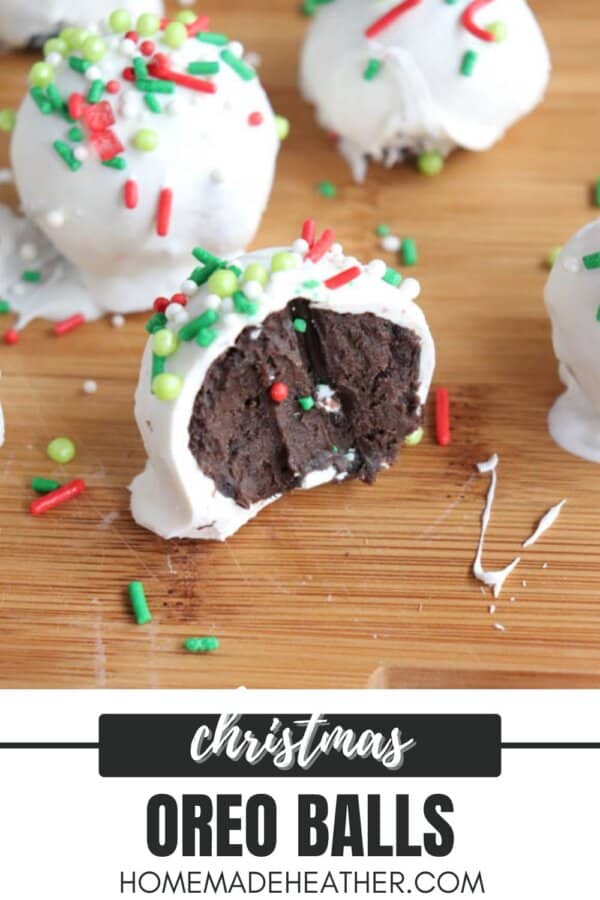 Close-up of Christmas Oreo balls on a wooden surface. One is cut in half, revealing a chocolate center. The balls are coated in white icing and decorated with red, green, and white sprinkles. Text reads Christmas Oreo Balls with a website below.