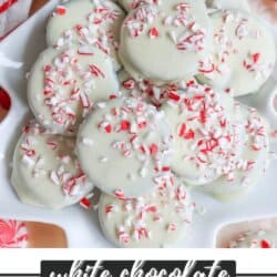 A plate of thin mint cookies, crafted from a cherished recipe, is coated in white chocolate and sprinkled with crushed peppermint candy. They rest on a festive background with red and white accents. Text overlay reads White Chocolate Thin Mint Cookies HomemadeHeather.com.