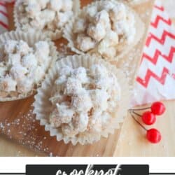 A wooden board displays several snowman balls covered in powdered sugar, placed in paper cups. A red and white patterned cloth and decorative red berries are nearby. Text at the bottom reads crockpot snowman balls homemadeheather.com.