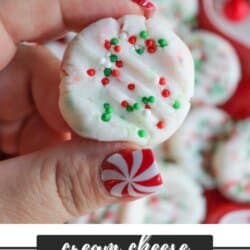 A close-up of a hand holding a cream cheese mint decorated with red and green sprinkles. The person has a peppermint nail design. The text reads, Cream Cheese Christmas Mints homemadeheather.com.